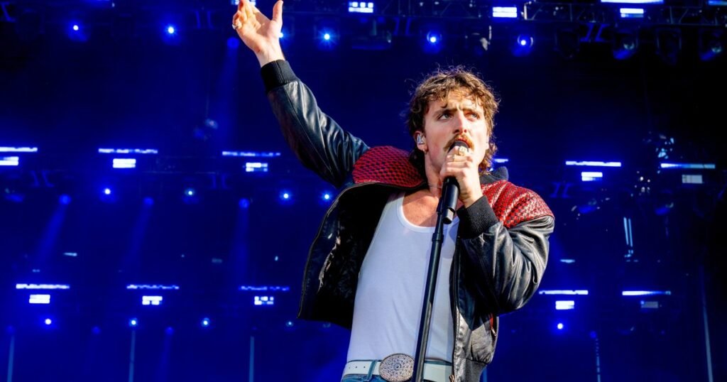 Benson Boone performing live on stage during a concert, wide shot of the singer mid-performance